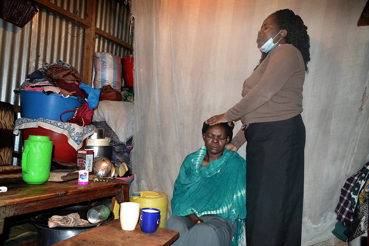 Roselyne Oyosa, a pastor at Huruma United Methodist Church in Nairobi, Kenya, prays for Agnes Nekesa at her house in the Huruma slums in Nairobi. Nekesa is battling breast cancer. Photo by Gad Maiga, UM News.
