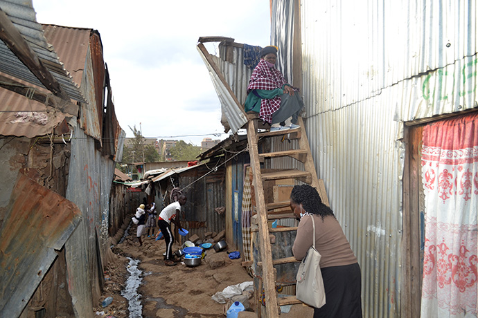 Pastor Roselyne Oyosa (front) visits with Agnes Nekesa at her home in the Huruma slums in Nairobi, Kenya. Nekesa, who has breast cancer, has to navigate several unstable wooden staircases to access her house. Photo by Gad Maiga, UM News.