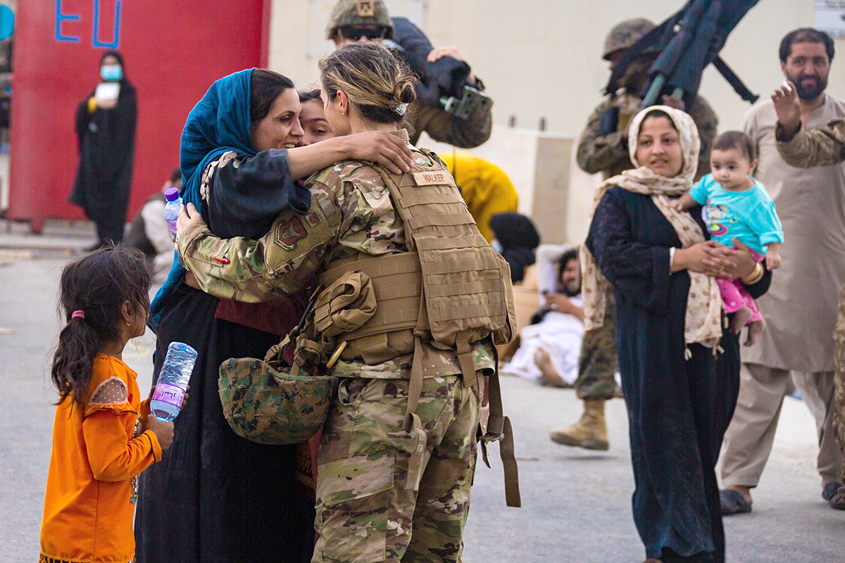 A U.S. airman with the Joint Task Force-Crisis Response embraces a mother after helping reunite her family at Hamid Karzai International Airport in Kabul, Afghanistan, Aug. 20. United Methodist churches, conferences, agencies and partner nonprofits are working to help arriving refugees make a good start in the U.S. Photo by Cpl. Davis Harris, U.S. Marine Corps.