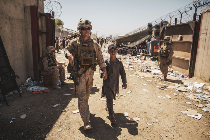 A U.S. Marine with the Special Purpose Marine Air-Ground Task Force-Crisis Response-Central Command escorts a youth to his family during an evacuation at Hamid Karzai International Airport in Kabul, Afghanistan, on Aug. 24. Photo by U.S. Marine Corps Staff Sgt. Victor Mancilla, courtesy of the U.S. Department of Defense.