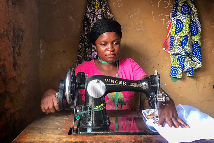 Henriette Kibibi, 22 ans, coud des uniformes dans son atelier près de Kindu, au Congo. Mère de deux enfants, Kibibi a reçu une formation professionnelle au Mama Lynn Center à Kindu qui l'aide à subvenir aux besoins de sa famille. Photo de Chadrack Tambwe Londe, UM News.