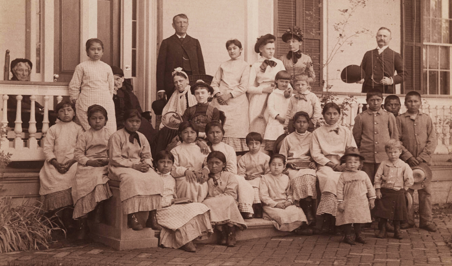 Fotografía del Capitán Pratt y estudiantes de la Escuela Industrial Carlisle, impresión fotográfica en blanco y negro, 13 cm x 21,5 cm. El capitán Richard Henry Pratt se desempeñó como director de la Escuela Industrial Carlisle, donde se envió a los/as nativos/as americanos/as. La fotografía debe haber sido tomada alrededor de 1900 (sin fecha). Pratt murió en 1924. Cortesía de la Colección de Yale de Western Americana, Biblioteca de Manuscritos y Libros Raros de Beinecke, Universidad de Yale, New Haven, Connecticut. Foto de dominio público a través de Wikimedia Commons.