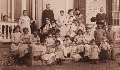 Fotografía del Capitán Pratt y estudiantes de la Escuela Industrial Carlisle, impresión fotográfica en blanco y negro, 13 cm x 21,5 cm. El capitán Richard Henry Pratt se desempeñó como director de la Escuela Industrial Carlisle, donde se envió a los/as nativos/as americanos/as. La fotografía debe haber sido tomada alrededor de 1900 (sin fecha). Pratt murió en 1924. Cortesía de la Colección de Yale de Western Americana, Biblioteca de Manuscritos y Libros Raros de Beinecke, Universidad de Yale, New Haven, Connecticut. Foto de dominio público a través de Wikimedia Commons. Fotografía del Capitán Pratt y estudiantes de la Escuela Industrial Carlisle, impresión fotográfica en blanco y negro, 13 cm x 21,5 cm. El capitán Richard Henry Pratt se desempeñó como director de la Escuela Industrial Carlisle, donde se envió a los/as nativos/as americanos/as. La fotografía debe haber sido tomada alrededor de 1900 (sin fecha). Pratt murió en 1924. Cortesía de la Colección de Yale de Western Americana, Biblioteca de Manuscritos y Libros Raros de Beinecke, Universidad de Yale, New Haven, Connecticut. Foto de dominio público a través de Wikimedia Commons.