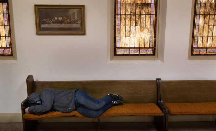 A guest of the day shelter sleeps on an extra pew in the fellowship hall at Trinity United Methodist Church. Photo by Mike DuBose, UM News.
