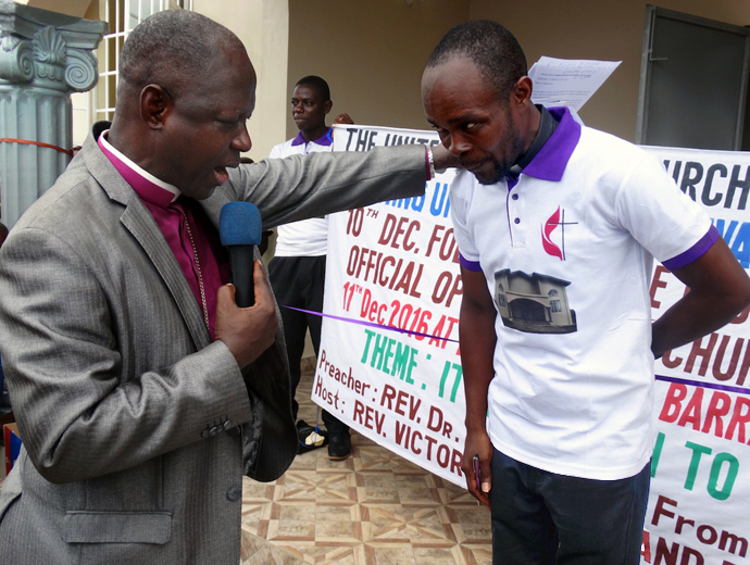 Sierra Leone Area Bishop John K. Yambasu (left) prays for the Rev. Victor Kainboy for his leadership of the church in Pujehun, southern Sierra Leone, in this 2017 file photo. Bishop Yambasu died in a car accident Aug. 16, 2020. The United Methodist University in Sierra Leone, which was founded by Yambasu, graduated the first set of students on Feb. 26. File photo by Phileas Jusu, UM News.