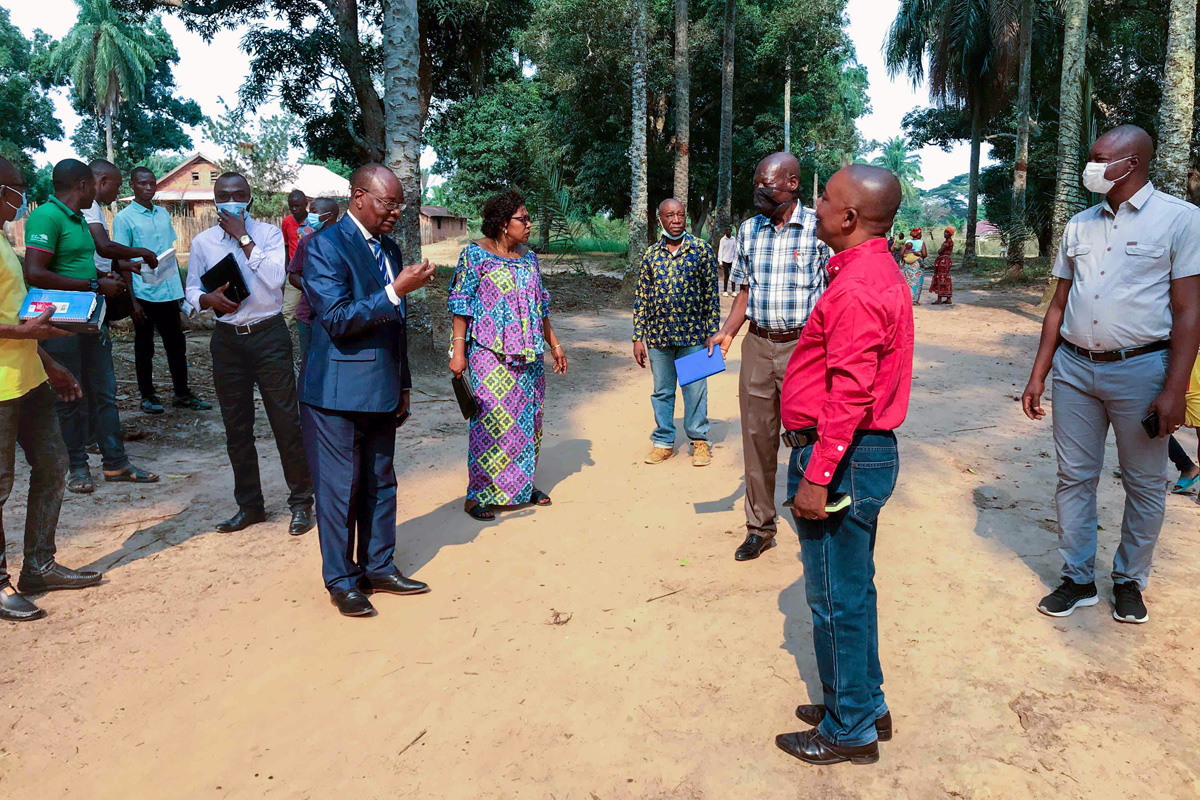 East Congo Episcopal Area Bishop Gabriel Yemba Unda (center left, in blue suit) and his wife, Dr. Marie-Claire Diandja (to his left), gather with clergy and lay leaders of the Tunda District on a tree-lined street leading to the local church. This year, United Methodists of the East Congo Episcopal Area are joyfully commemorating the centennial of the church in eastern Congo. Photo by Chadrack Londe, UM News.