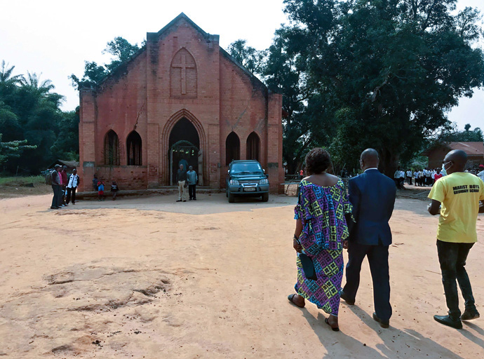 East Congo Episcopal Area Bishop Gabriel Yemba Unda (in blue suit) and his wife, Dr. Marie-Claire Diandja, visit Tunda Chapel, the first church built in the Tunda United Methodist Mission by the first American missionaries in 1922. Photo by Chadrack Londe, UM News.