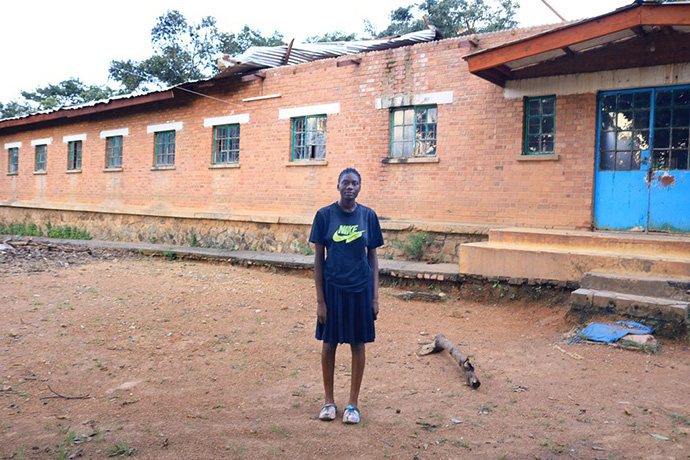 Kibambe Kazadi Gracia, étudiante à l'école secondaire Mulungwishi, se tient devant le dortoir des filles où une partie du toit a été emportée par le vent à la Mission Mulungwishi, une Mission Méthodiste Unie dans la Région Épiscopale du Sud-Congo/Zambie. Photo par John Kaumba, UM News.