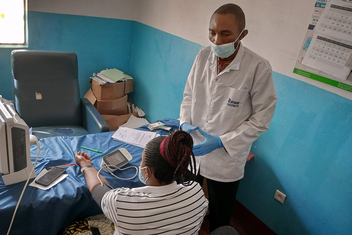 Dr. Patrick Kilunji, director of United Methodist Shungu Clinic in Kamina, Congo, shows a pregnant woman how to take her own blood pressure at the clinic. In partnership with Harper Hill Global and other organizations, the clinic and North Katanga Episcopal Area are helping educate people in rural villages about hypertension and the risks for pregnant women. Photo by the Rev. Betty Kazadi Musau, UM News.