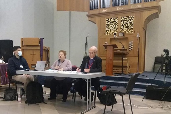 United Methodist Bishop Patrick Streiff (right) leads the March 31 session of the Bulgaria-Romania Provisional Annual Conference, with help from the Rev. Margarita Todorova, interpreter, and the Rev. Tsvetan Iliev, conference secretary. Later in the four-day meeting, conference members voted unanimously to leave The United Methodist Church for the new, traditionalist Global Methodist Church, which begins operations May 1. Photo courtesy of the Bulgaria-Romania Conference.