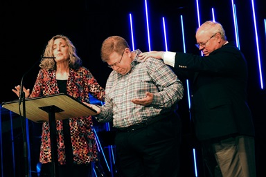 The Revs. Carolyn Moore and Keith Boyette pray for the Rev. Jay Therrell (center) at the Wesleyan Covenant Association’s May 7 gathering in Avon, Ind. The day before, the WCA’s Global Legislative Assembly elected Therrell as the new WCA president. He’ll succeed Boyette, who will be top executive of the new Global Methodist Church. Photo by Sam Hodges, UM News. The Revs. Carolyn Moore and Keith Boyette pray for the Rev. Jay Therrell (center) at the Wesleyan Covenant Association’s May 7 gathering in Avon, Ind. The day before, the WCA’s Global Legislative Assembly elected Therrell as the new WCA president. He’ll succeed Boyette, who will be top executive of the new Global Methodist Church. Photo by Sam Hodges, UM News.