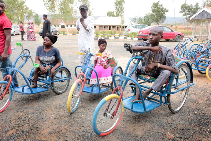 Recipients sit on new tricycles that were donated through a partnership between the United Methodist Southern Nigeria Conference and the Beautiful Gate Handicap Center in Jalingo, Nigeria. The bikes allow people with mobility issues to pedal with their hands. Photo by Ezekiel Adams, UM News.
