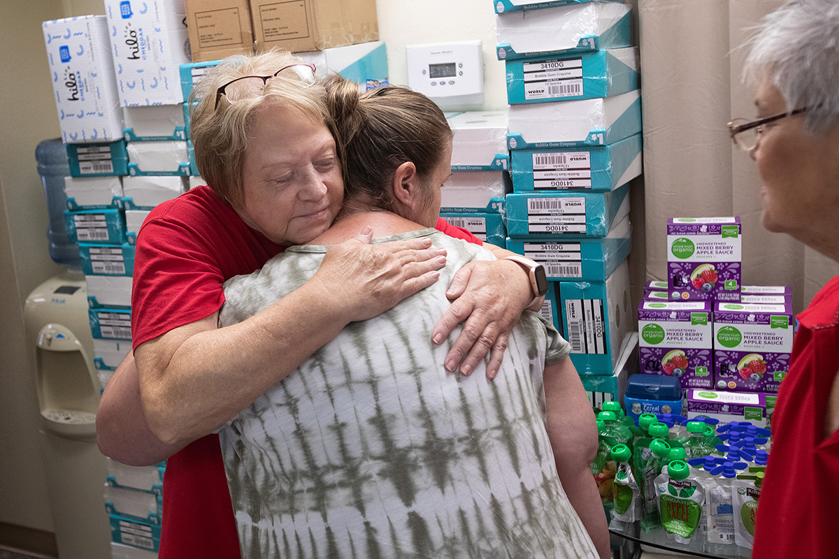 La voluntaria Rose Calhoun (izquierda) abraza a Rosemarie Peak sobreviviente de la inundación, quien estaba recogiendo suministros de socorro en la Misión Metodista Unida de la Montaña en Jackson, Kentucky. A la derecha está la voluntaria Debbie Holcomb. Las voluntarias son miembros de la Iglesia Metodista Unida de Hampton en Kentucky.
