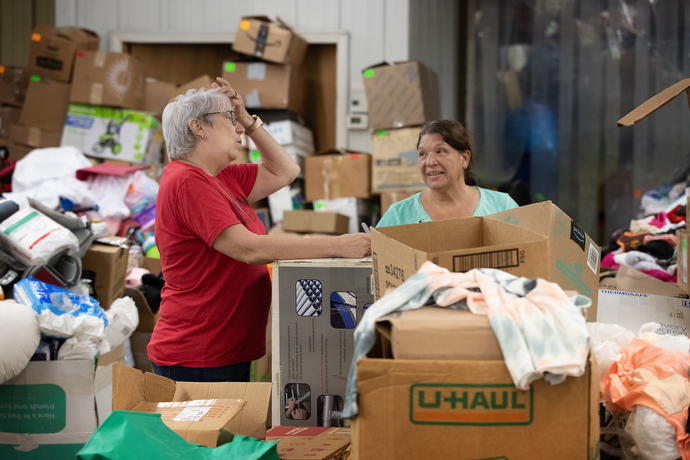 Karen Bunn (left) visits with Dolly Barnett amid growing piles of relief supplies donated for flood survivors at United Methodist Mountain Mission. Bunn is the center’s executive director and Barnett is employed there. Photo by Mike DuBose, UM News.