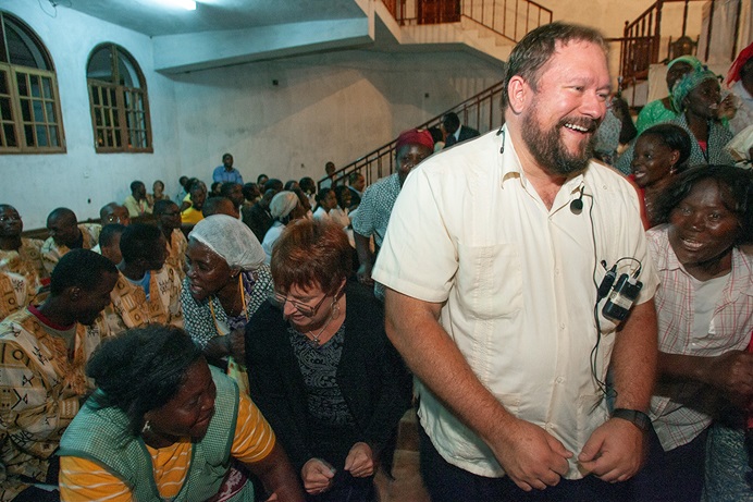 Donald Reasoner (front), then coordinator of language interpretation services for The United Methodist Church’s Board of Global Ministries, is welcomed to the Icolo e Bengo United Methodist Church in Luanda, Angola, site of the 2006 West Angola Annual Conference. Reasoner, the son of missionary parents, has spent more than 30 years providing interpretation and translation for the denomination. To Reasoner’s right is Kathy L. Gilbert, a writer for UM News, now retired. File photo by Mike DuBose, UM News.