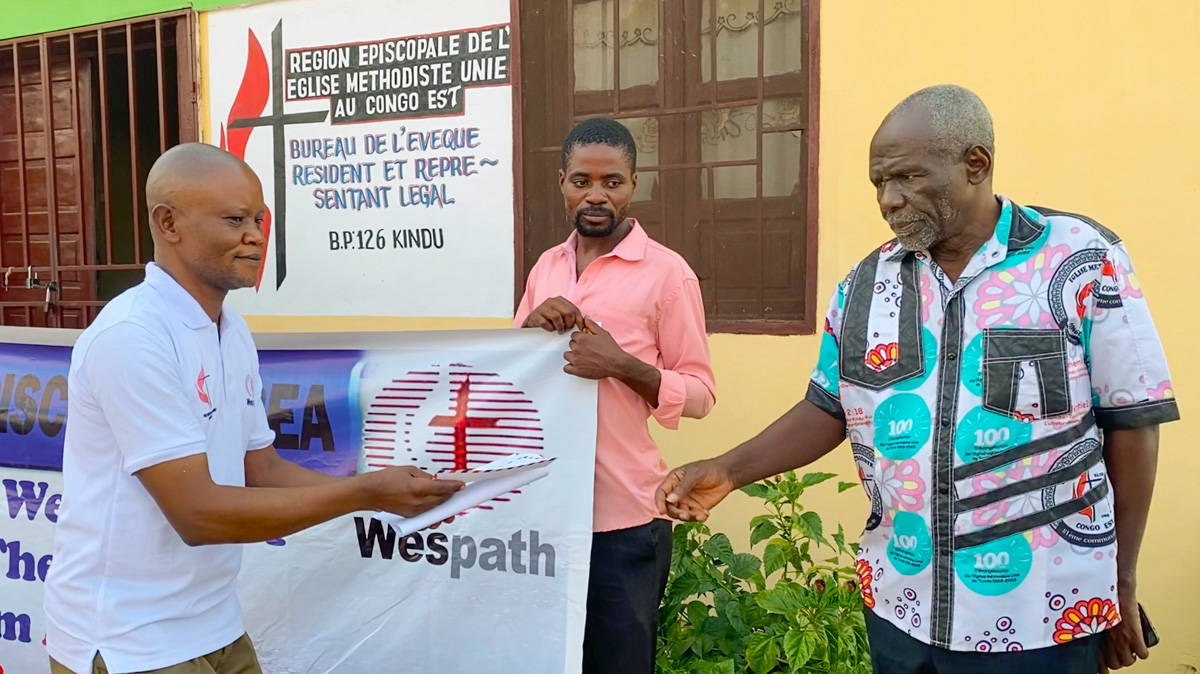 Pastor Kanya Kamahiro Georges (at right) receives his stipend during a presentation ceremony held at the Eastern Congo episcopal office. The assistance from Wespath allows 12 student pastors to buy food and provide for other needs for eight months. Photo by Chadrack Tambwe Londe, UM News.