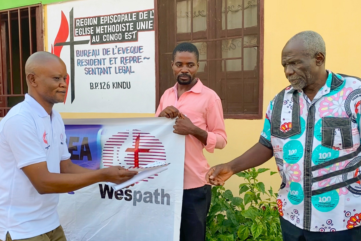 Pastor Kanya Kamahiro Georges (at right) receives his stipend during a presentation ceremony held at the Eastern Congo episcopal office. The assistance from Wespath allows 12 student pastors to buy food and provide for other needs for eight months. Photo by Chadrack Tambwe Londe, UM News.
