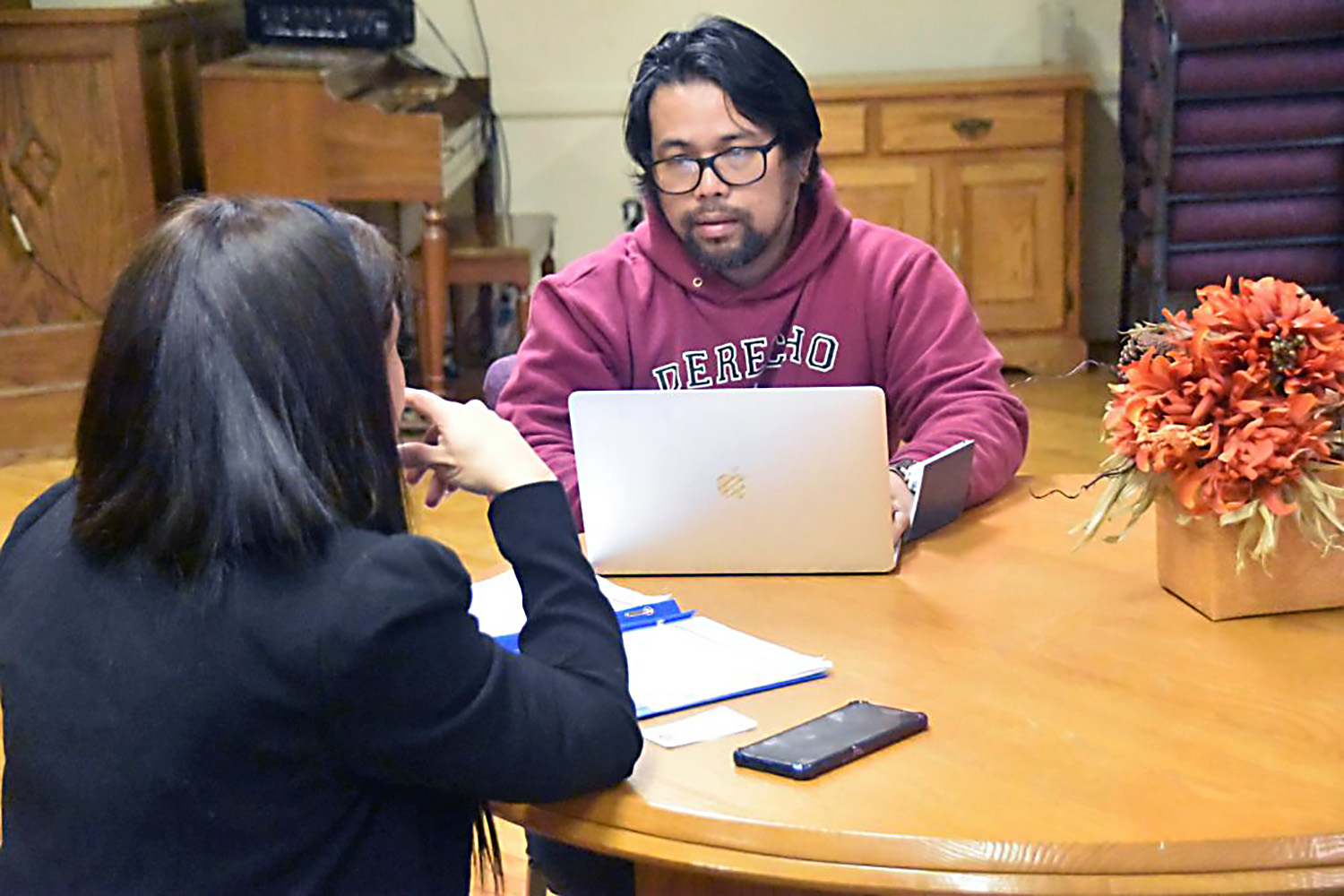 A la derecha, Bonn Aure, asistente legal de Justicia para Nuestros Vecinos​(JFON por sus siglas en inglés) conversa con una inmigrante. Foto cortesía de JFON.