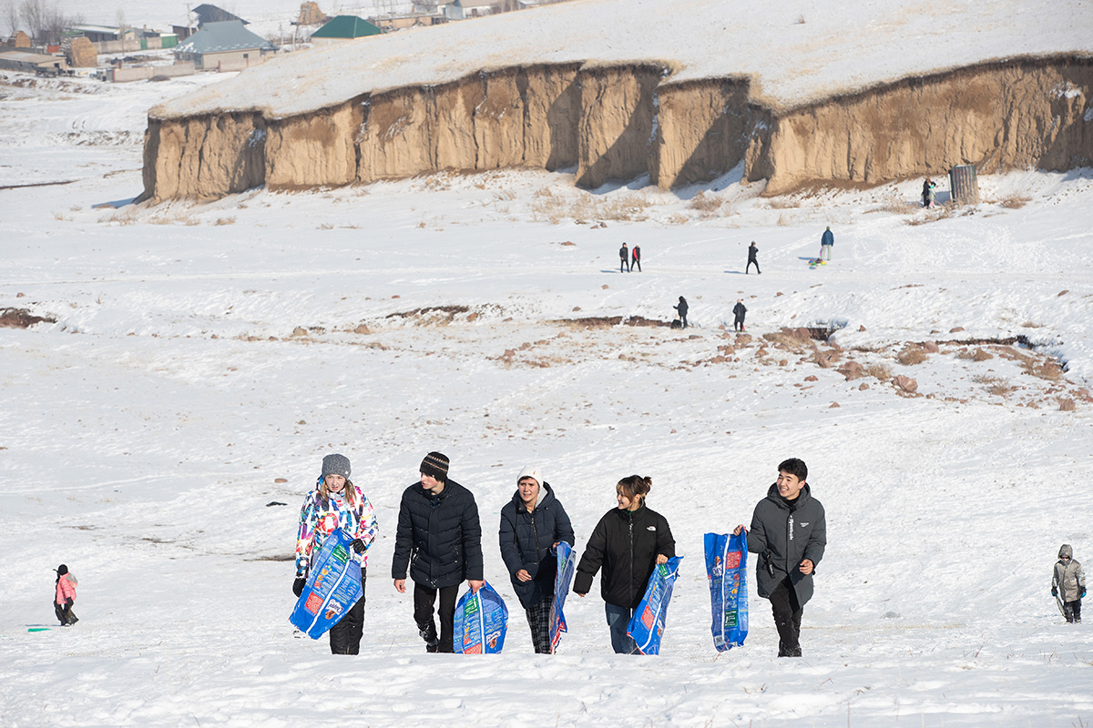 Young people from Livespring United Methodist Church and guests make their way into the Tian Shan mountains near Kara-Balta, Kyrgyzstan, for a day of sliding in the snow. They are carrying empty pet food bags to use as makeshift sleds. Photo by Mike DuBose, UM News.
