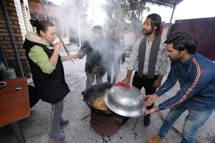 The Rev. Nellya Shakirova (left) samples the dinner being cooked outdoors by students from Pakistan who attend Bishkek United Methodist Church. The students (from left) are: Muslam Hanif, Sanwal Shabir, Yashib Nayab and Thomson Gill. Photo by Mike DuBose, UM News.