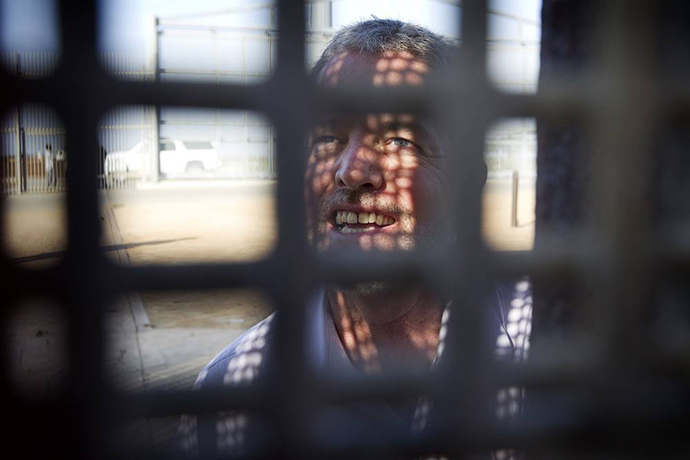 The Rev. John Fanestil, an elder from the California-Pacific Conference and leader of the organization Friends of Friendship Park, stands behind the steel mesh of the U.S.-Mexico border fence while preparing for a cross-border communion service. File photo by Mike DuBose, UM News.