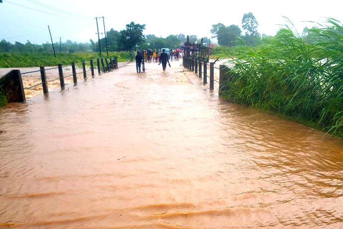 People cross a flooded bridge in Milange, Mozambique, in the wake of Cyclone Freddy. “We have never experienced so much rain and heavy winds in just a couple of days,” said the Rev. Maria Joao Budula, Zambezia North District superintendent. “Everywhere we look, we see water and destruction.” Photo by Zenaido Castigo.