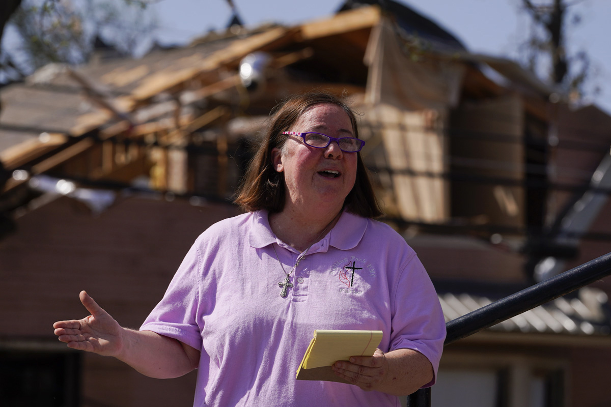 The Rev. Mary Stewart of Rolling Fork United Methodist Church leads a prayer as people worship on the steps of the church on March 26 in Rolling Fork, Miss. At least 25 people were killed by tornadoes that tore through the state on March 24, destroying buildings and knocking out power as severe weather moved through several southern states. (AP Photo/Julio Cortez)