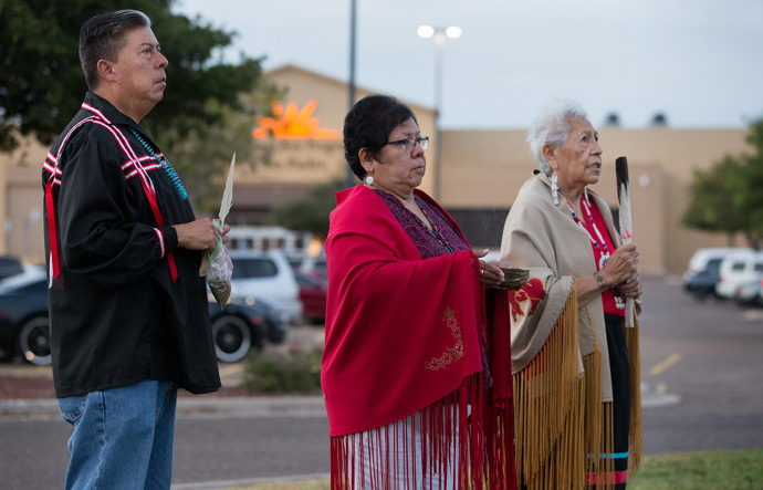 Bishop David Wilson (left) and the Rev. Donna Pewo (center) of The United Methodist Church’s Oklahoma Indian Missionary Conference join with Native American scholar Henrietta Mann in a prayer service for immigrant children held at the Casa Padre detention center, visible behind them, in Brownsville, Texas, in 2018. File photo by Mike DuBose, UM News.