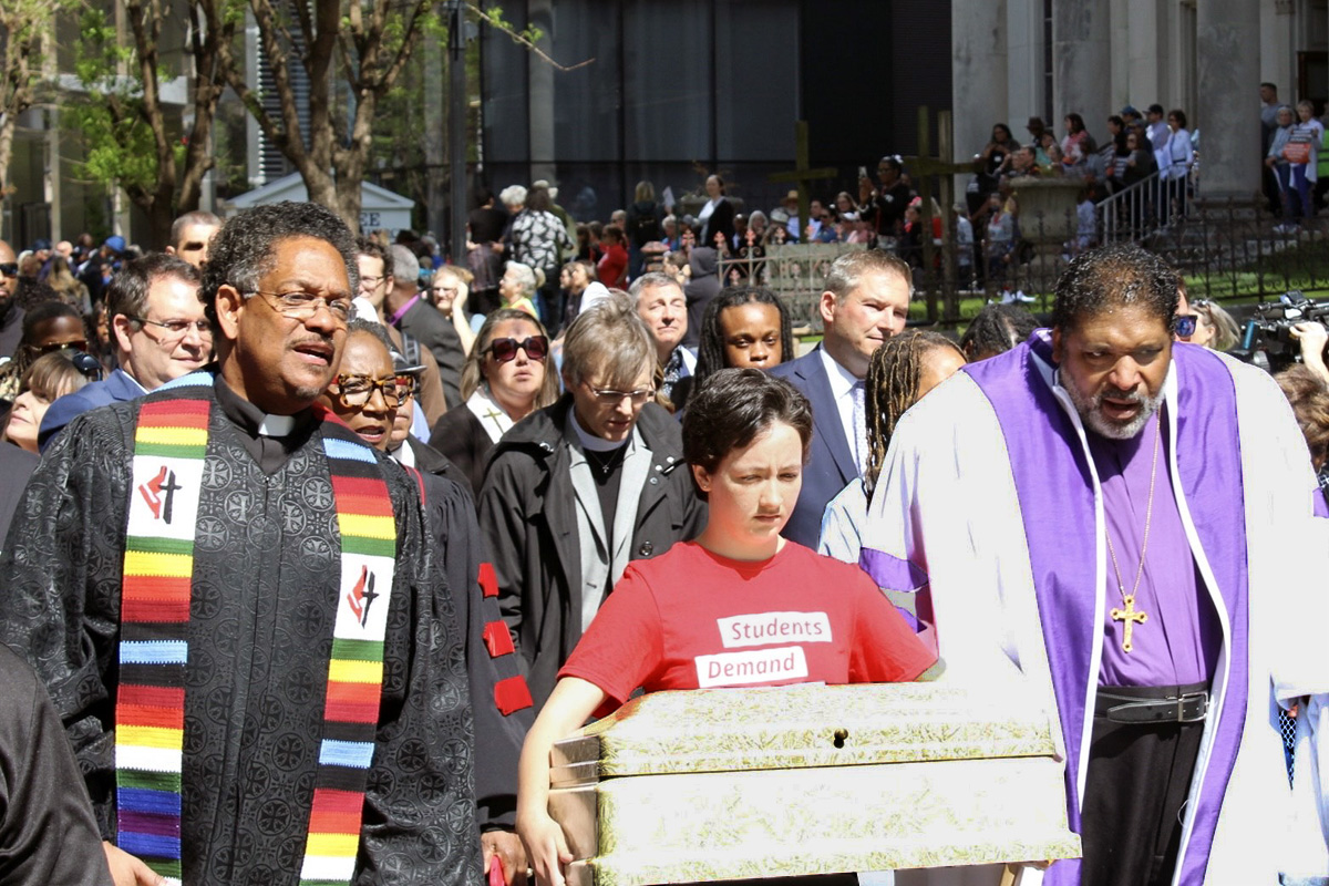 The Rev. Stephen Handy (left), pastor of McKendree United Methodist Church, and the Rev. William Barber II (right) join Shannon Felder as she carries a child’s casket during an April 17 march in Nashville, Tenn., to protest gun violence and push for gun safety legislation. Five caskets and an urn were carried from McKendree United Methodist Church to the Tennessee State Capitol, one for each victim of a March 27 school shooting in Nashville. Photo by Vernon Jordan, UM News.