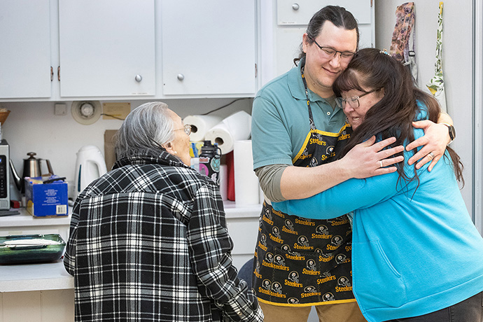 Nina Gorman (right) hugs the Rev. Murray Crookes in the kitchen at Every Nation United Methodist Church in Anchorage, Alaska, where Crookes and his family host a weekly fellowship meal and Bible study. Photo by Mike DuBose, UM News.
