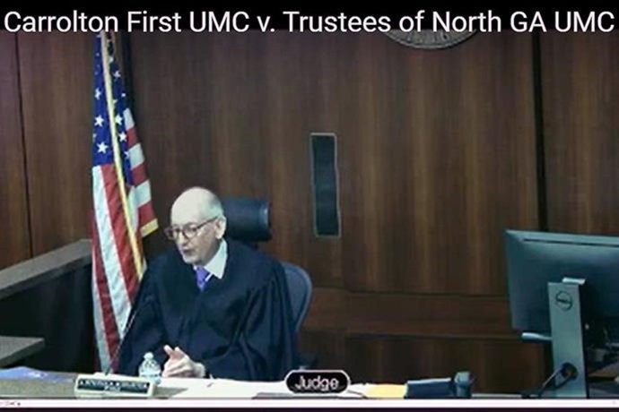 Cobb County Superior Court Judge J. Stephen Schuster, at the end of a daylong hearing, rules from the bench that more than 180 churches in the North Georgia Conference can proceed with The United Methodist Church’s disaffiliation process. The conference had paused disaffiliation votes in the wake of what it called defamatory misinformation. Screengrab courtesy of Cobb County Superior Court via YouTube by UM News.