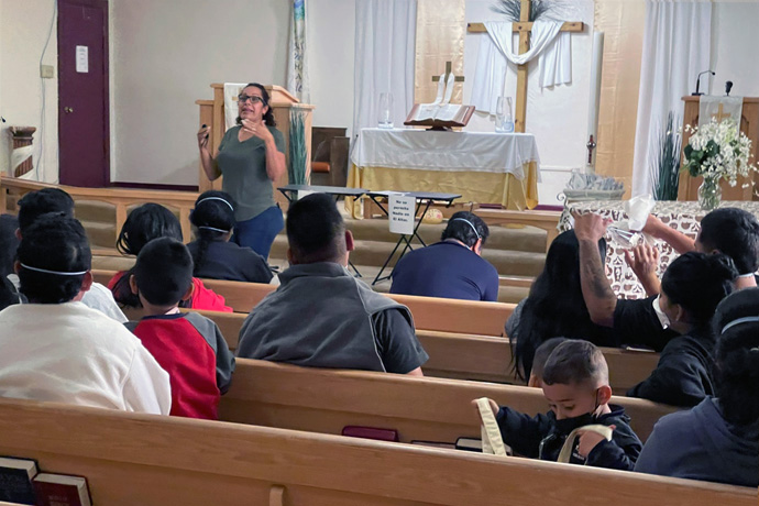 Susana Torres, shelter manager at El Calvario United Methodist Church in Las Cruces, New Mexico, gives an orientation talk on May 15 to asylum seekers who arrived on a U.S. Immigration and Customs Enforcement bus. The church, with the help of partners, offers food, clothing and temporary shelter to migrants who have been allowed to stay in the U.S., pending a court hearing on their asylum request. They typically are on the road again soon, connecting with family members or other sponsors elsewhere in the country. Photo courtesy of El Calvario United Methodist Church.