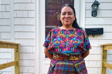 Maria Chavalan Sut stands in front of the three-bedroom home she rents with her four children in Charlottesville, Va. Chavalan Sut, who fled her native Guatemala in 2015, spent three years in sanctuary at Wesley Memorial United Methodist Church before receiving a Stay of Removal in 2021. Photo © Richard Lord. 