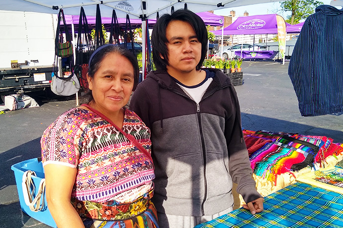Maria Chavalan Sut and her son Ulil sell goods at the City Market in Charlottesville, Va. Ulil and his three siblings came to the U.S. in 2022 to be reunited with their mother. Like her, they are seeking asylum. Photo © Richard Lord.