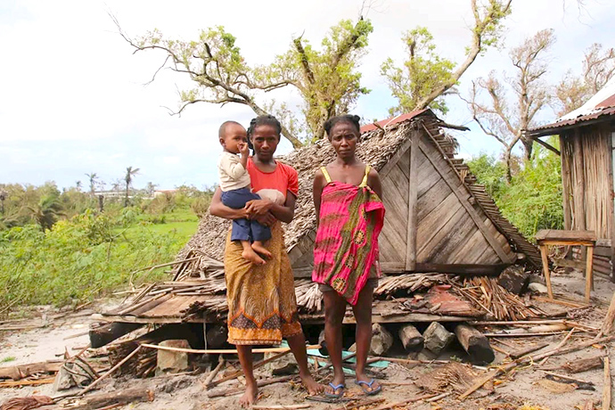 Uma mãe com dois filhos fica em pé ao lado dos restos de sua casa, que foi destruída pelo ciclone Freddy no distrito de Mananjary, em Madagascar. Foto de Justin Rakotoarimanana.