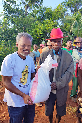 Bodo Abani Marielle (with red hat) receives foodstuff from Pastor Jean Aime Ratovohery of Ambodifasika United Methodist Church during a mission trip to Andranomavo, Madagascar. Church members distributed food to families affected by Cyclone Freddy, which devastated the region earlier this year. Photo by Justin Rakotoarimanana.