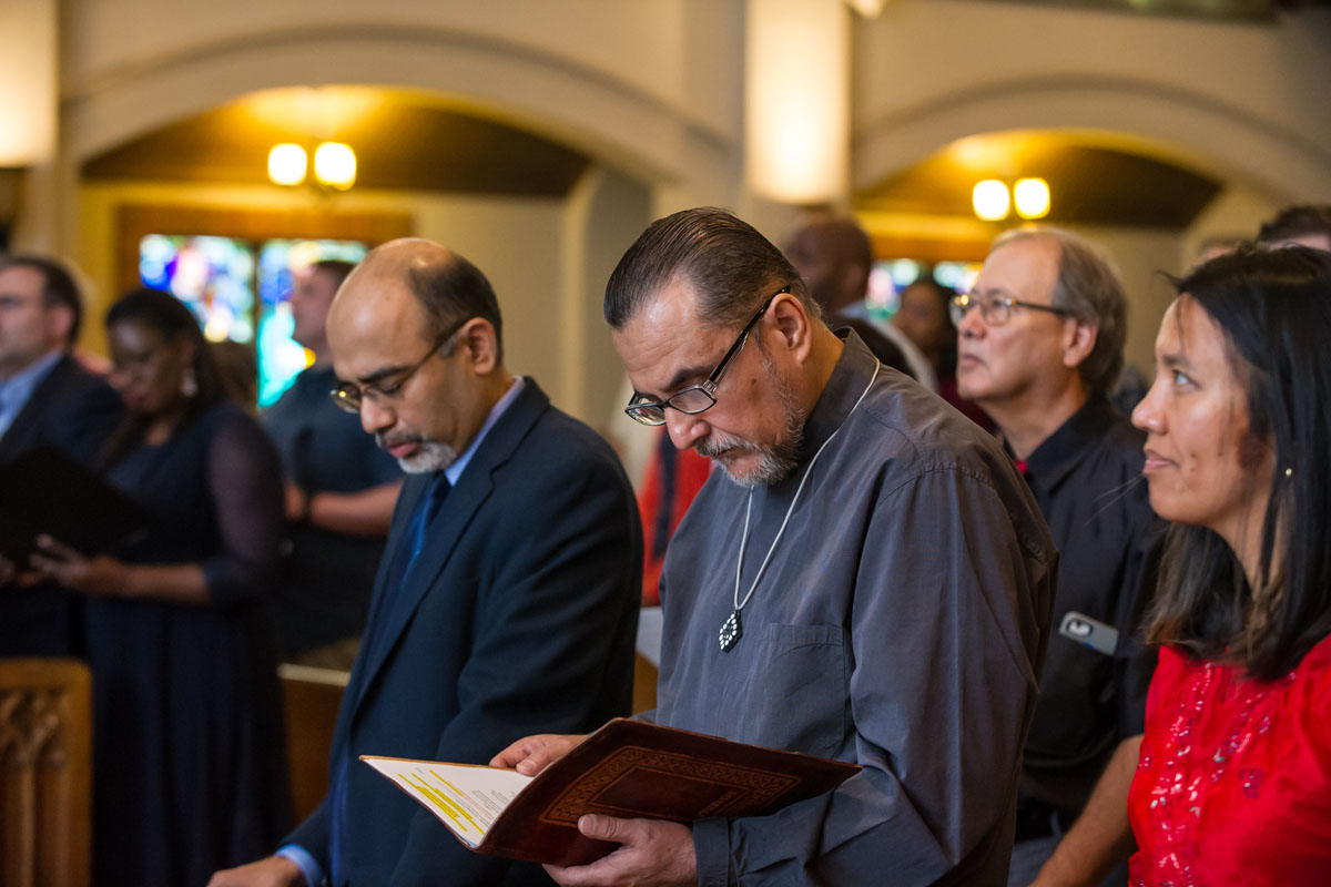 The Rev. Edgar Avitia Legarda (center) follows along in prayer during the missionary blessing service at Atlanta’s Grace United Methodist Church in May 2018. Avitia, a longtime staff member of the United Methodist Board of Global Ministries, died on June 27. Roland Fernandes, later top staff executive of Global Ministries, is to his right. File photo by Hector Amador, Global Ministries.