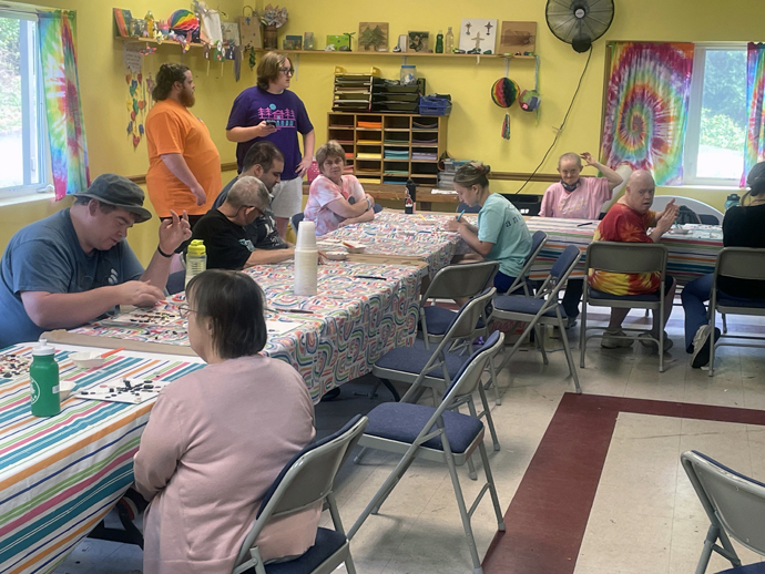 Counselor Joe Ward (in orange shirt) helps campers at Innabah Camp and Retreat Center as they make artwork using buttons on June 29. Photo by Jim Patterson, UM News.