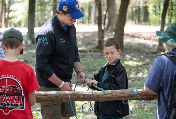 Kyler Martell of Boy Scout Troop 398 learns to tie a taut-line hitch with help from instructor Marcus Leikam at the Boxwell Scout Reservation. Photo by Mike DuBose, UM News.