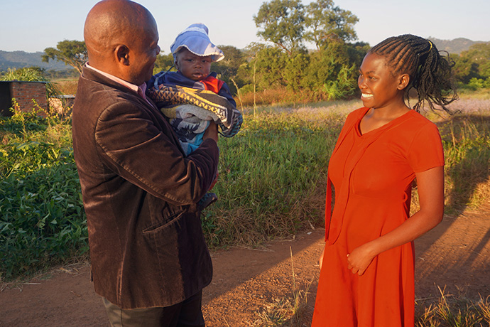 Associate Pastor Mabasa Muzhizhizhi (left) holds Evans, the son of Vimbai Mlambo (right), during an evangelical visit to Pepsia Farm in April. Mlambo, who lives at the farm, recently joined The United Methodist Church. Farm owners say the church activities have led to positive changes for many of the workers and their families. Photo by Kudzai Chingwe, UM News.
