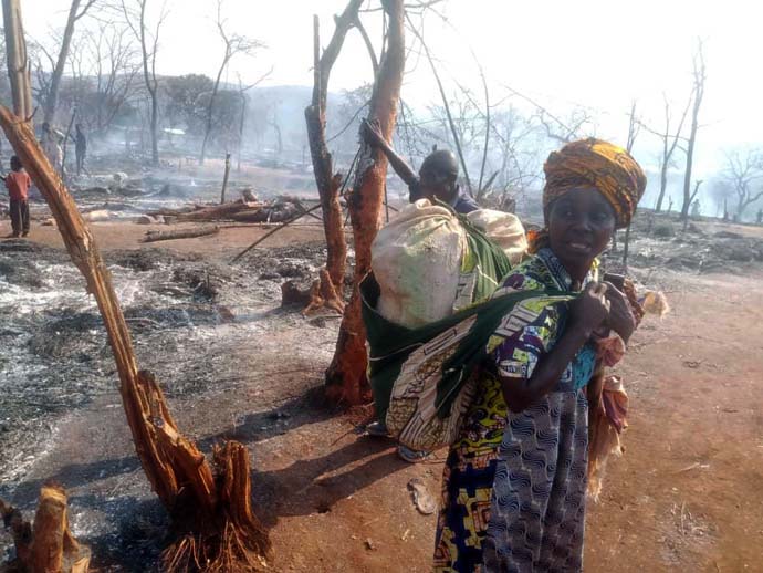 Asende Lumumba Milando, 40 ans, se tient dans le camp de déplacés de Malicha, dans le territoire de Fizi, au Sud-Kivu (Congo), où 1 000 abris de fortune ont brûlé lors d'un incendie le 19 août. Cette mère de sept enfants a perdu tout ce qu'elle possédait dans l'incendie. Photo de Philippe Epanga, avec l'aimable autorisation du Bureau de Gestion des Catastrophes de la Région Épiscopale du Congo Est.