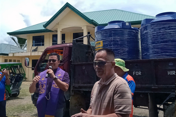 Davao Area Bishop Israel M. Painit (left) presents three 2,000-liter polyethylene tanks to neighborhood leader Manolito Payot for the communities of Novele, Rosario and Agusan del Sur, Philippines. The tanks were installed at a community evacuation building and two daycare centers. Photo courtesy of the Rev. Dan Reuben L. Sison.