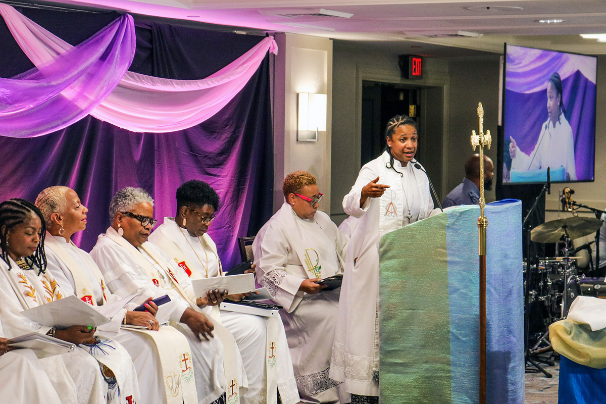 The Rev. Dawn Hand, president of Black Clergywomen of The United Methodist Church, speaks at the group’s national meeting, held in Washington July 31-Aug. 2. Seated from left are Bishops Cynthia Moore-Koikoi, Tracy Smith Malone, LaTrelle Easterling, Delores J. “Dee” Williamston and the Rev. Karli Pidgeon, superintendent of the Baton Rouge and New Orleans districts in the Louisiana Conference. Photo by Marcharkelti McKenzie. 