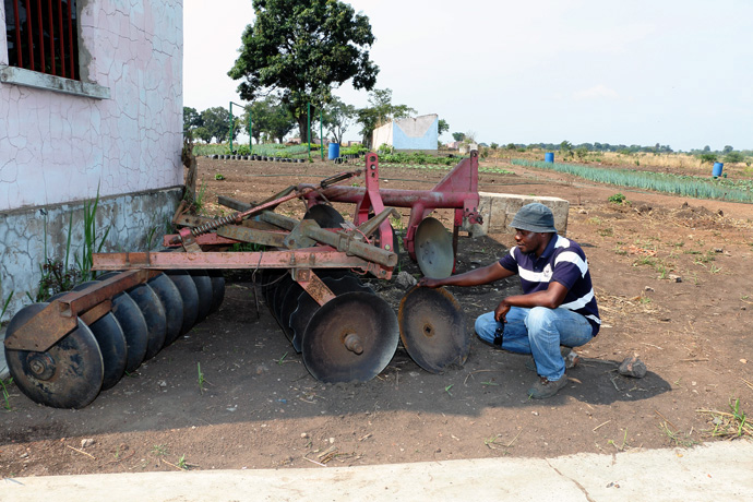 Kutela Katembo examina uma charrua de disco desmontado na missão de Quéssua na Conferência de Leste de Angola. Katembo supervisiona o programa agrícola lá. Foto de arquivo do Rev. Armando Rodriguez.