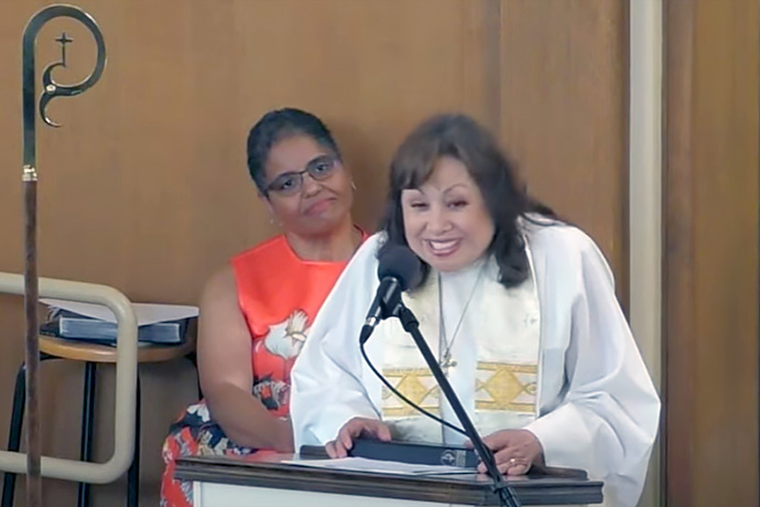 Bishop Minerva G. Carcaño preaches at a “Welcome Home” service Oct. 1 at First United Methodist Church in Sacramento, Calif. She preached just days after her return to the California-Nevada Conference after an 18-month suspension. Behind her is Pam Kelly, who led worship music. Screengrab courtesy of the California-Nevada Conference via YouTube by UM News.