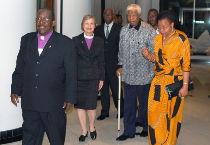 A Bispa Janice Huie (segunda a partir da esquerda), então presidente do Conselho dos Bispos da Metodista Unida, acompanha Nelson Mandela e a sua esposa, Graça Machel, enquanto o Bispo João Somane Machado (à esquerda) de Moçambique lidera o caminho. Mandela e Machel fizeram uma visita surpresa durante o jantar de 5 de Novembro de 2006, na reunião do Conselho dos Bispos em Maputo, Moçambique. Mandela e Machel ambos tinham raízes Metodistas. Mandela morreu em 2013 em Houghton, Joanesburgo. O Bispo Machado morreu em 25 de Outubro. Foto de arquivo de Stephen Drachler, Notícias da MU. 