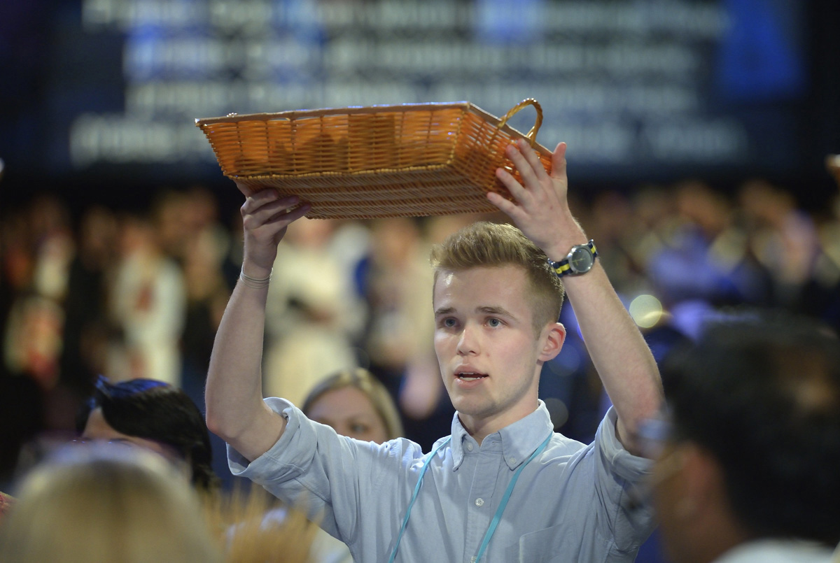 A young man helps bring forth the offering collected during the opening worship service of the 2016 United Methodist General Conference in Portland, Ore. The General Council on Finance and Administration board has approved a 3% raise for bishops and a 3% increase for office support but also suggested an additional $20 million will need to be cut on the 2025-2028 budget going before General Conference. File photo by Paul Jeffrey, UM News.