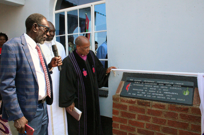 Bishop Eben K. Nhiwatiwa (right) dedicates the new United Methodist Chitenderano Church sanctuary, which was built in partnership with Union United Methodist Church in South Carolina and Home Is Best, a group of former Chitenderano church members now living in other countries. Edward Mukoyi (left), Chitenderano lay leader, reads a plaque during the Sept. 24 dedication in Rusape, Zimbabwe. Photo by Kudzai Chingwe, UM News.