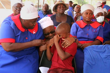 Women console Kupakwashe Mberi, 8, who got emotional after Bishop Eben K. Nhiwatiwa recognized him for his drumming performance during the United Methodist Zimbabwe East Conference Healing Convention at Mufusire Farm. “He gave me a token of appreciation and words of encouragement and wisdom. It touched me,” the boy said. Photo by Kudzai Chingwe, UM News. Women console Kupakwashe Mberi, 8, who got emotional after Bishop Eben K. Nhiwatiwa recognized him for his drumming performance during the United Methodist Zimbabwe East Conference Healing Convention at Mufusire Farm. “He gave me a token of appreciation and words of encouragement and wisdom. It touched me,” the boy said. Photo by Kudzai Chingwe, UM News.