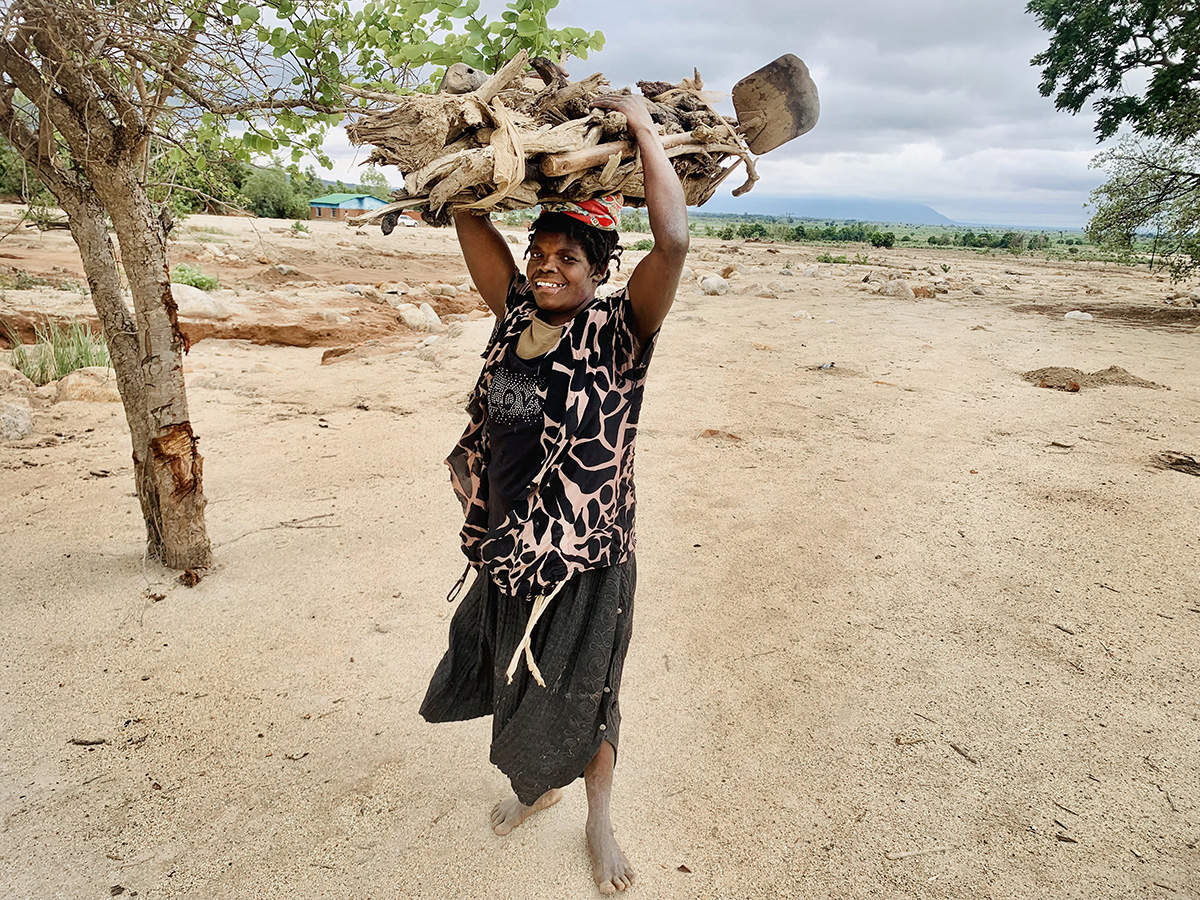 Rebecca Navaya carries firewood to her family’s temporary home in Nkhulambe, Malawi, near the border with Mozambique. Navaya is among survivors of Cyclone Freddy who are rebuilding their lives with support from the United Methodist Committee on Relief. Photo by Francis Nkhoma, UM News. 